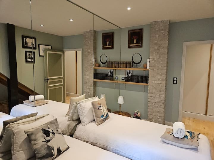 Chambre avec grand miroir et deux lits parure de lit blanche_