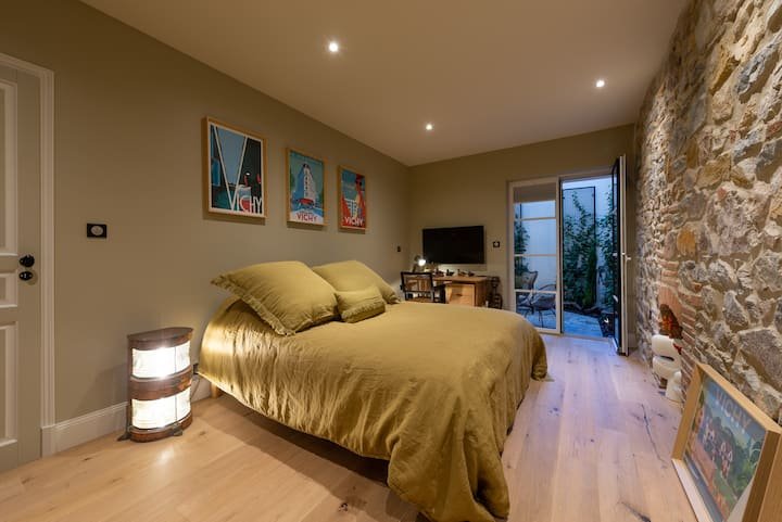 Chambre parentale avec pierre apparente et parure de lit jaune duplex 75m2 Vichy