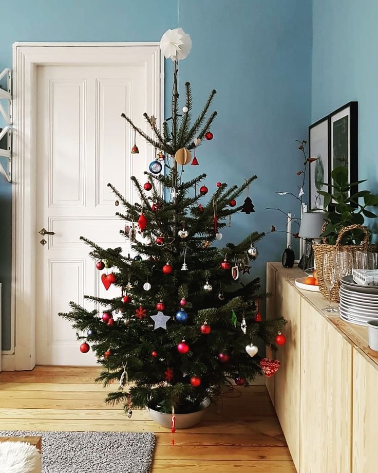 Déco sapin de Noël 2025 en rouge et argenté dans salon bleu glacier scandinave