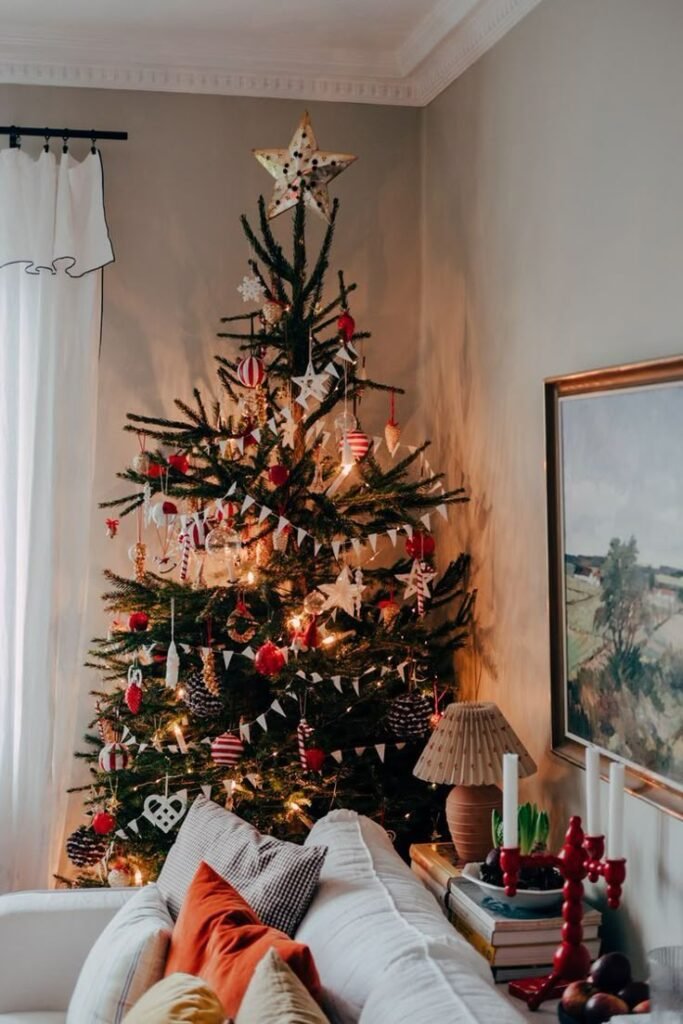 Déco sapin de noël 2025 avec guirlande blanche et boules rouges dans salon blanc et orange chaleureux