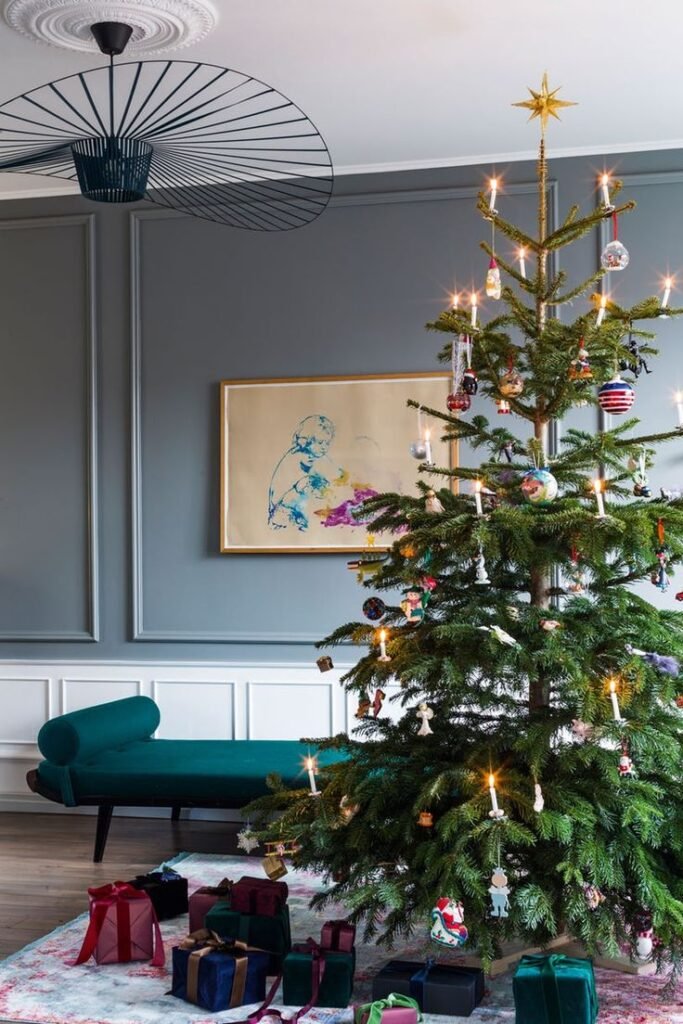 Déco sapin de noël 2025 dans salon gris avec banquette verte boules et bougies suspendues