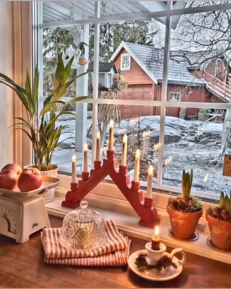 Décoration fenêtre de Noël avec bougeoir rouge et plantes paysage enneigé