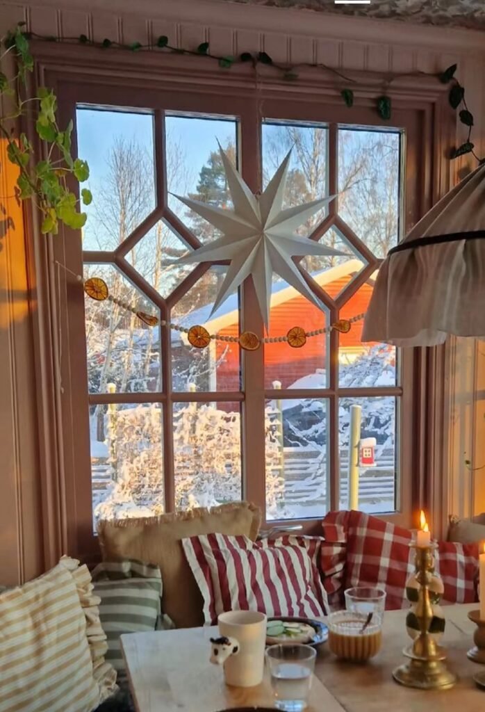 Fenêtre de chalet décoré pour Noël vue sur paysage enneigé