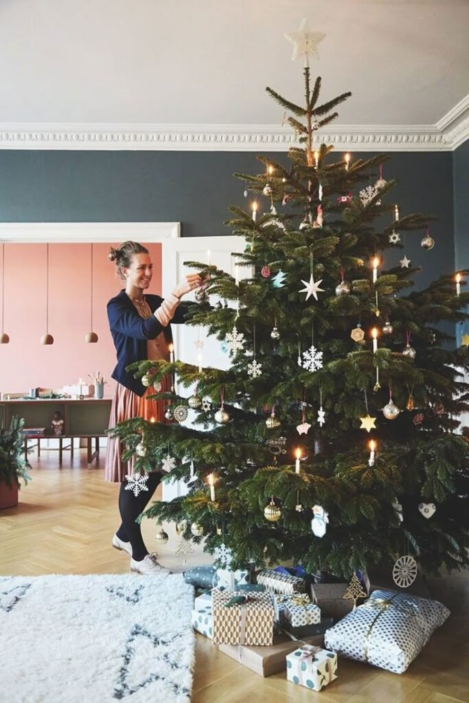 Inspiration grand sapin de noël 2025 avec bougies et flocons de neige dans salon gris